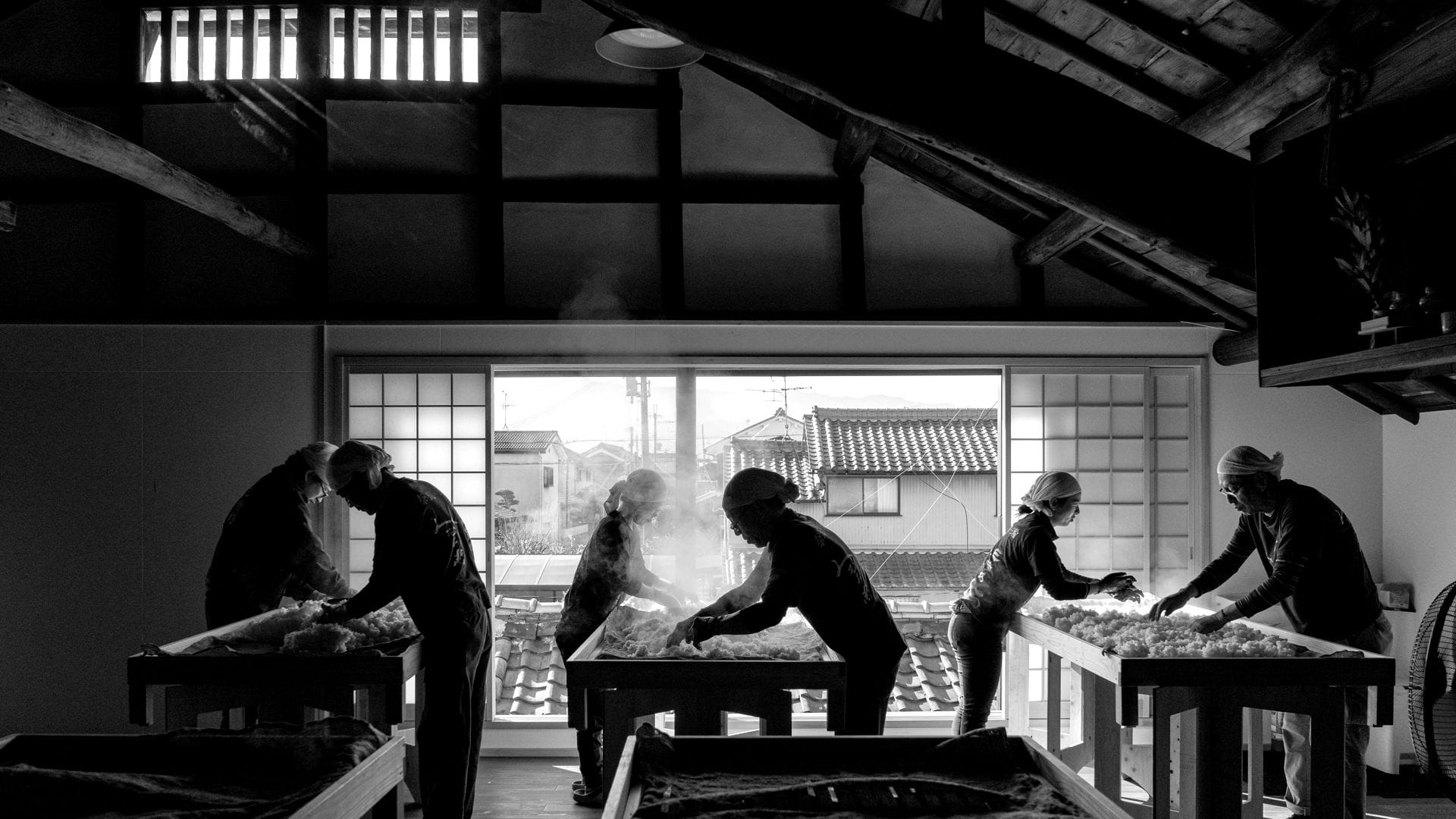 A brewer tending koji in the koji room